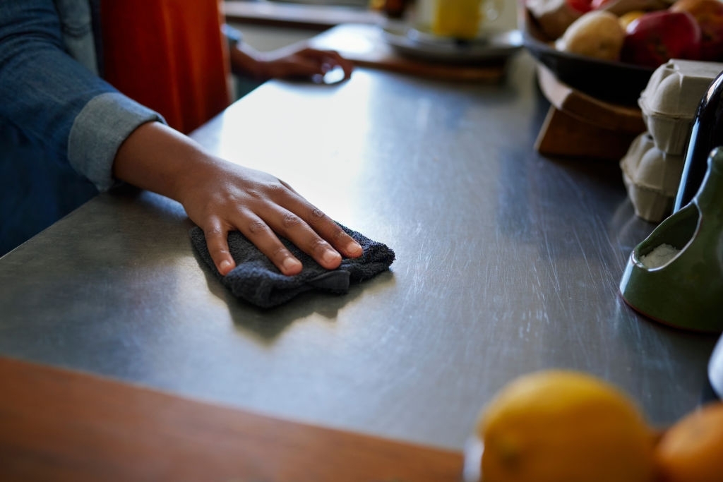 Cropped shot of an unrecognizable woman wiping the kitchen counter at home